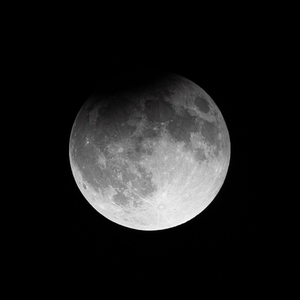 Partial lunar eclipse with Earth’s shadow covering the upper edge of the moon