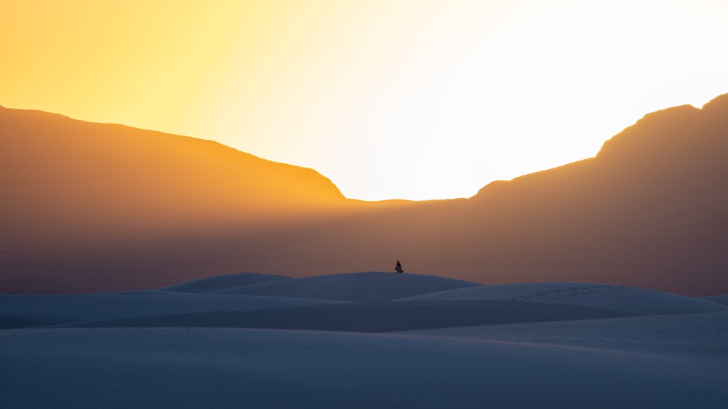 Cloudless sunset at White Sands National Park with mountains silhouetted against a gold and blue gradient